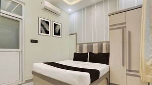 A bedroom with a bed, a wardrobe, and two wall-mounted air conditioning units. - Super Hotel O Maharshi Valmiki Airport  (Faizabad)
