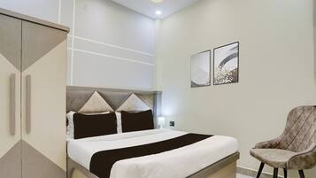 A modern bedroom with a bed, a chair, and artwork on the wall.