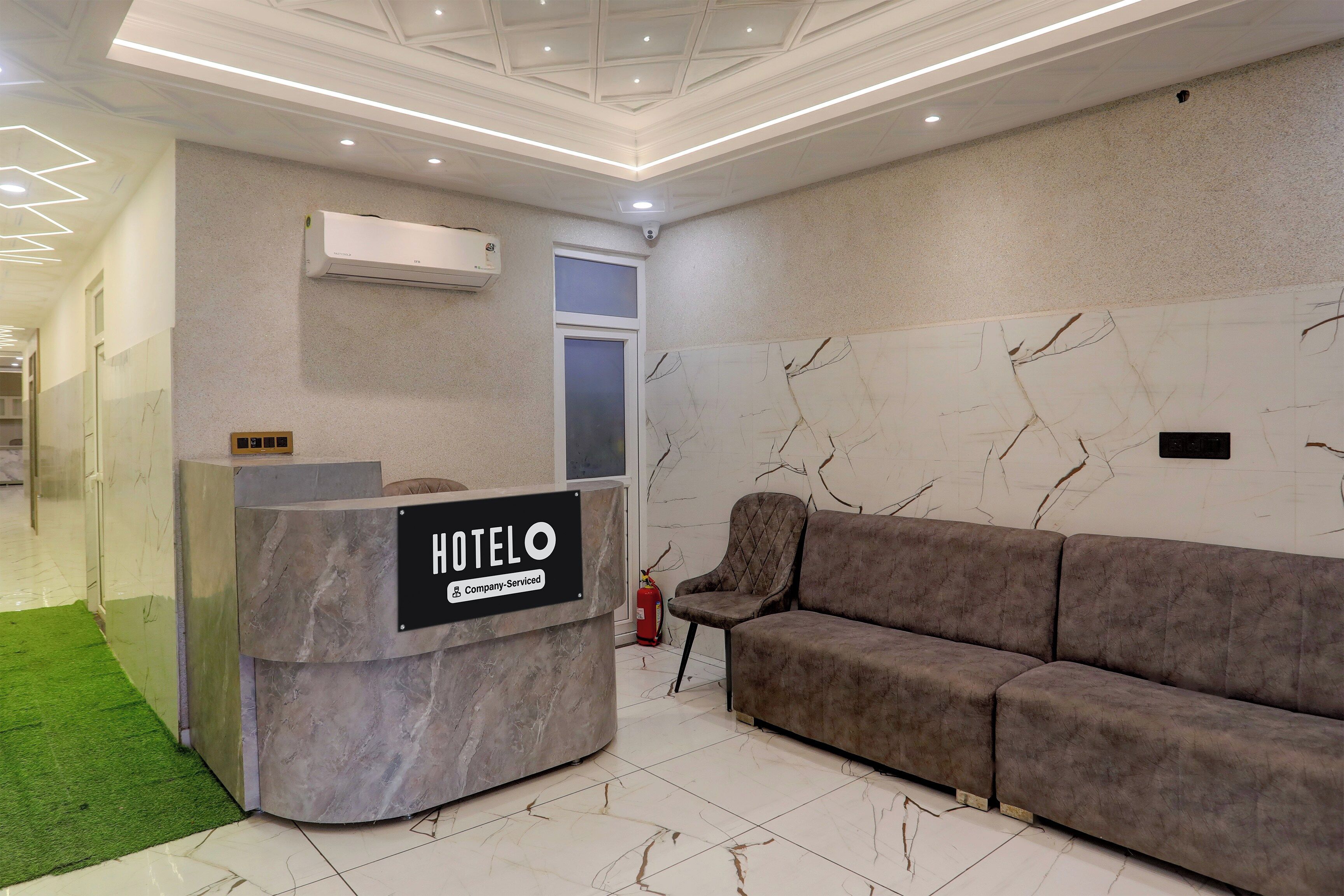 A hotel reception area with a marble reception desk, a sofa, and a fire extinguisher.