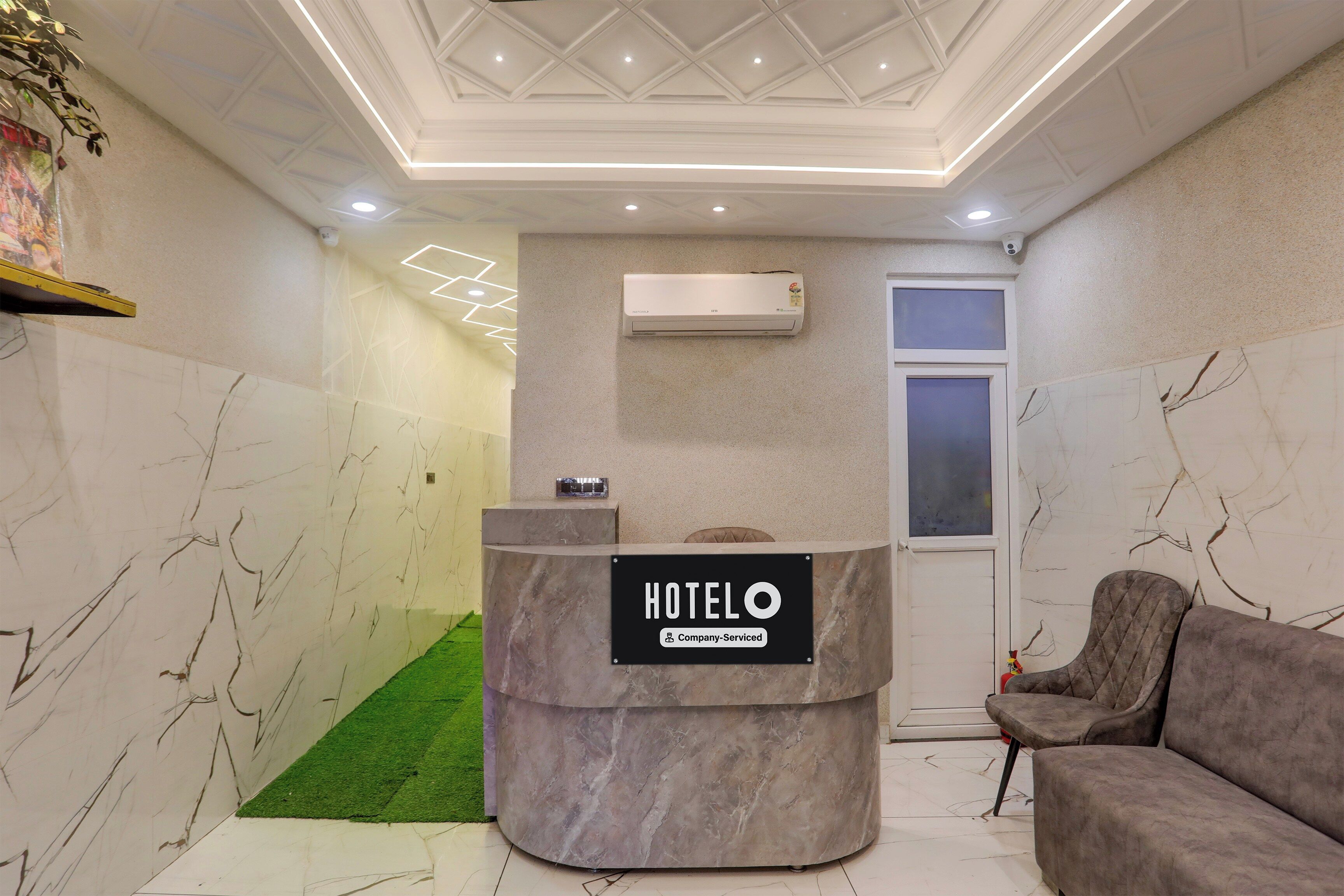 A hotel reception area with a marble reception desk, a grey sofa, and a wall-mounted air conditioner.