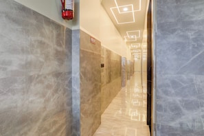 Corredor com paredes de mármore e placa de saída de incêndio.