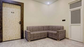 A room with a marble door, a grey sectional sofa, and a white door with a frosted glass panel.