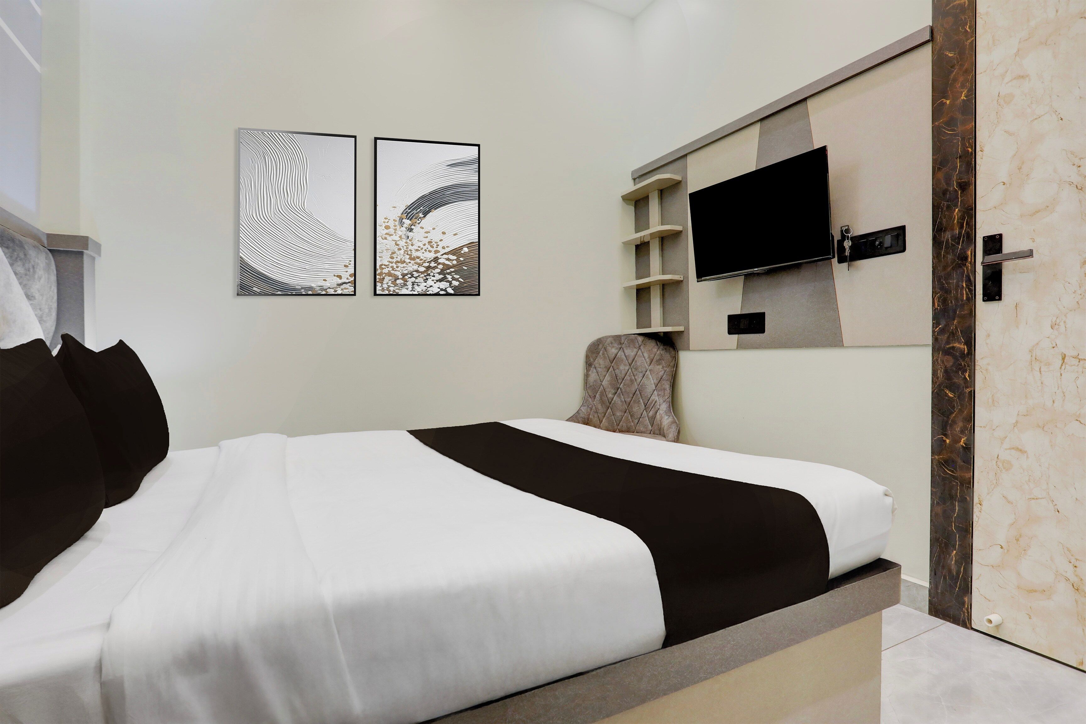 A modern bedroom with a bed, a television mounted on the wall, and two wall art pieces.