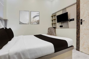 Quarto moderno com cama, televisão fixada na parede e duas obras de arte na parede.