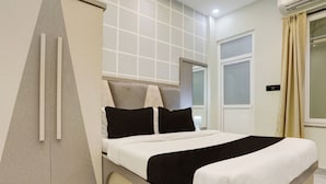 A modern hotel room with a bed, a wardrobe, and a window. - Super Hotel O Maharshi Valmiki Airport  (Faizabad)