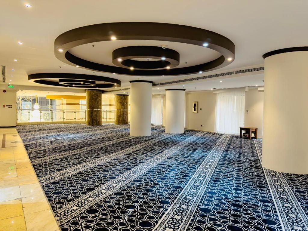 A spacious interior with a patterned carpet, large pillars, and a modern ceiling design.