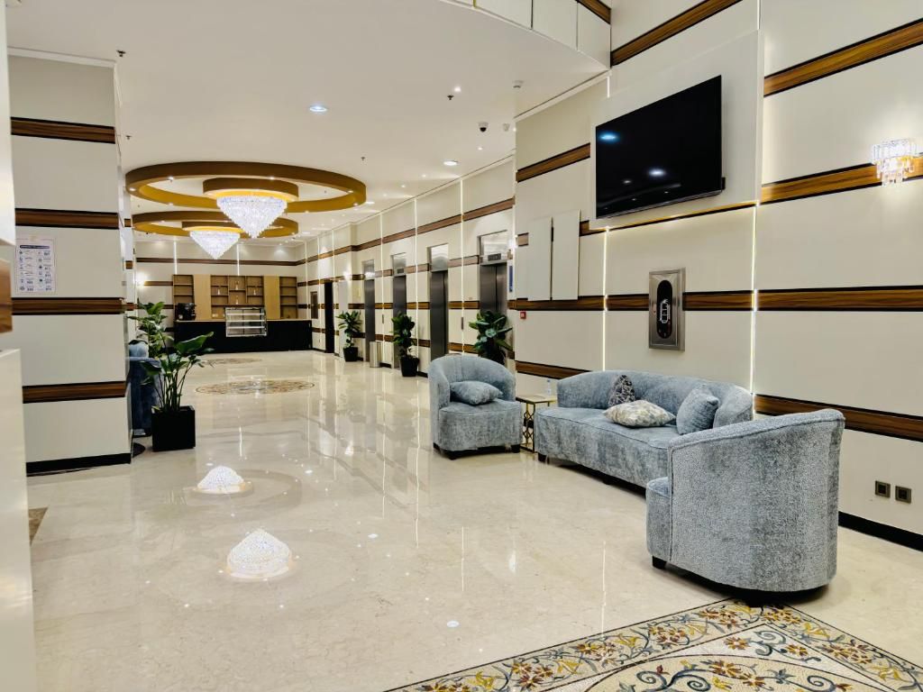 A hotel lobby with a reception desk, seating area, and a TV mounted on the wall.