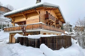 A wooden chalet with a balcony, surrounded by snow. - Stylish Morzine chalet, centrally located with hot tub (Morzine)