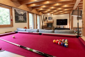 A pool table with balls, a sofa, a television, and a fireplace. - Stylish Morzine chalet, centrally located with hot tub (Morzine)