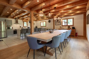 A modern kitchen with a wooden ceiling, a dining area with a long table and chairs, and a refrigerator. - Stylish Morzine chalet, centrally located with hot tub (Morzine)