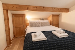 A bedroom with a bed, pillows, a quilted bedspread, and rolled towels on the bed. - Chalet Doux Abri, sleeps 12, hot tub, sauna (Morzine)
