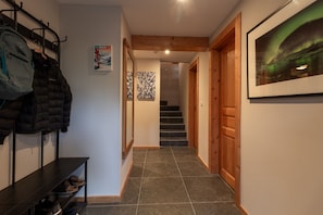 A hallway with a coat rack, a shelf with shoes, a staircase, and a framed picture on the wall. - Chalet Doux Abri, sleeps 12, hot tub, sauna (Morzine)