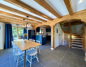 A spacious kitchen with wooden beams, a dining area with a table and chairs, and a staircase leading to an upper level. - Chalet Doux Abri, sleeps 12, hot tub, sauna (Morzine)
