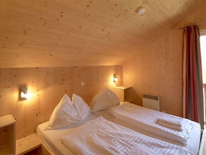 A wooden room with a bed, pillows, a nightstand, and a wall-mounted light fixture. - Chalet #12b With IR Sauna & Whirlpool (Sankt Georgen am Kreischberg)