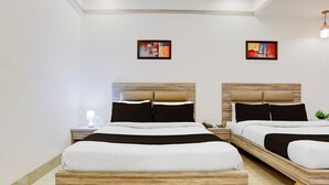 Habitación de hotel con dos camas, una mesita de noche con lámpara y obras de arte en las paredes.