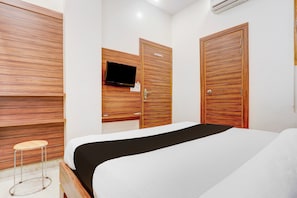 A hotel room with a bed, a TV mounted on a wooden wall, and a wooden wardrobe. - Collection O Haldwani Railway Junction (Haldwani)