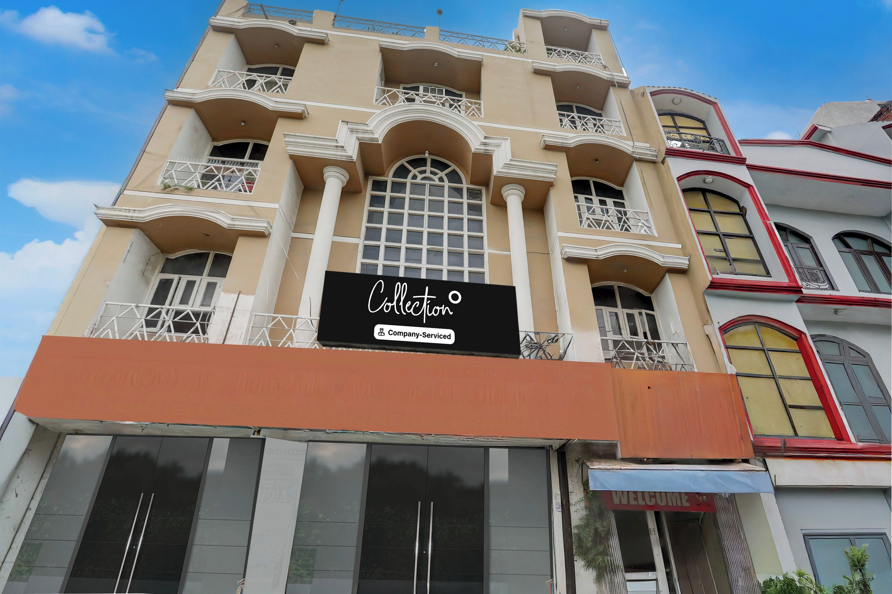 Un edificio con varios balcones, un letrero llamativo que dice 'Collection Company-Service' y un cartel de 'BIENVENIDOS' en la entrada.