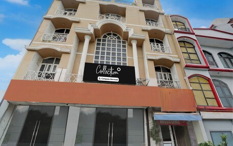 A building with multiple balconies, a prominent sign reading 'Collection Company-Service', and a 'WELCOME' sign at the entrance.