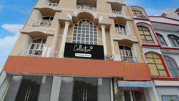 Un edificio con varios balcones, un letrero llamativo que dice 'Collection Company-Service' y un cartel de 'BIENVENIDOS' en la entrada.