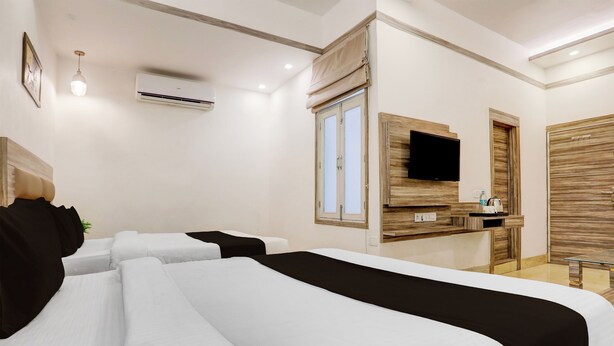 Una habitación de hotel con cama, televisión, escritorio y ventana con cortinas.