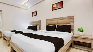 A hotel room with two beds, a nightstand with a plant, and artwork on the walls.