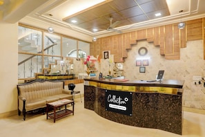 A reception area with a reception desk, a sofa, a coffee table, and a staircase. - Collection O Haldwani Railway Junction (Haldwani)