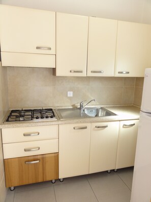 A kitchen with a gas stove, stainless steel sink, and light-colored cabinets. - Apartment With Terrace in Village With Pools (San Michele al Tagliamento)