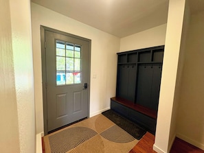 A hallway with a gray door, a bench, and a dark wooden bench with hooks. - SlopeTown Retreat - Big Sky Meadow (Big Sky)