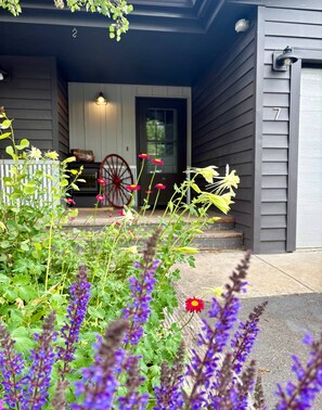 A porch with a red wheelbarrow, a white door, and a number '7' on the wall. - SlopeTown Retreat - Big Sky Meadow (Big Sky)