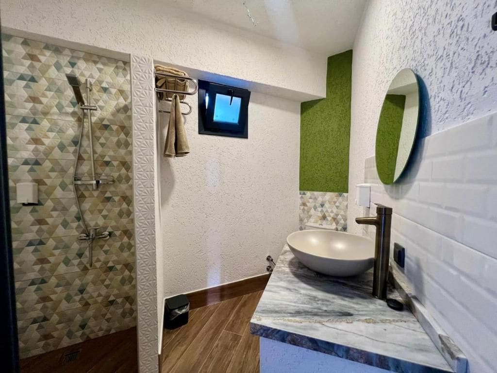 Un bany amb dutxa, un lavabo i un mirall.
