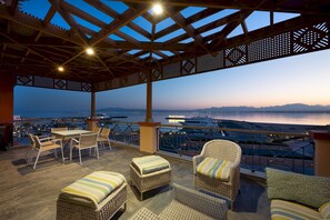 A covered outdoor seating area with wicker furniture and a view of the sea. - Vesta - Luxury Apt - 3BR - Marina Soma Bay (Soma Bay)