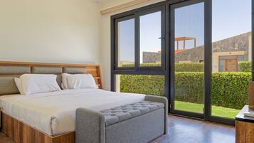 Un dormitorio con una cama grande, cabecera de madera y vistas a una pared de piedra y follaje exterior.
