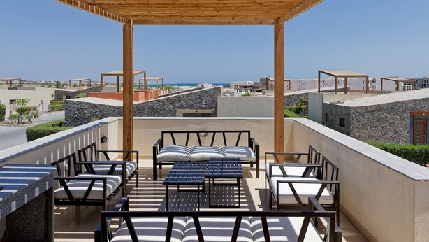 Terraço no telhado com área de estar externa, vista para o mar e céu limpo.