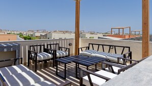 Terraço no telhado com mobiliário para área externa, pérgola e vista da paisagem urbana.