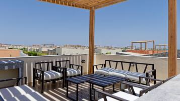 Una terraza en la azotea con mobiliario exterior, una pérgola y vistas a la ciudad.