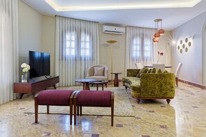 A modern living room with a flat-screen TV, a sofa, a chair, a coffee table, and a patterned rug. - Luxury APT - 2BR - South Teseen I (New Cairo)