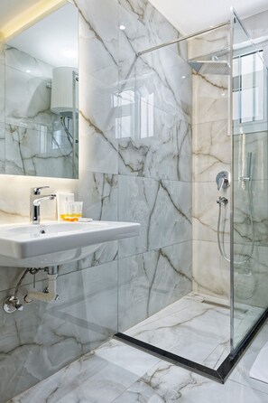 A modern bathroom with a marble sink, a glass shower enclosure, and a large mirror. - Luxury APT - 2BR - South Teseen I (New Cairo)