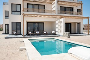 Ein modernes, zweistöckiges Gebäude mit Schwimmbad, Außenbereich und überdachter Terrasse.