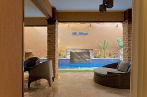 A resort's outdoor seating area with wicker furniture and a pool. - Vesta - Luxury APT - 2BR - South Academy II (Cairo)