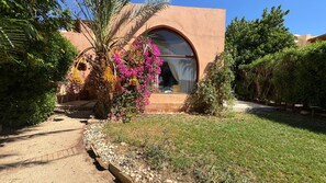 A building with an arched window and a garden with various plants and flowers. - Vesta - Luxury Twin House - 3BR - Nubia (El Gouna)