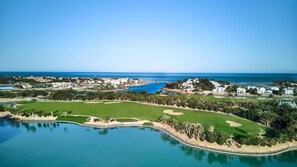 A coastal golf course with a large body of water, green fairways, and a clear view of the ocean. - Vesta - Luxury APT - 2BR - Water Side (El Gouna)