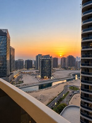 A high-rise building with a view of a cityscape at sunset. - Vesta - Luxury Studio - Hera Tower (Dubai)