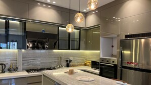 Cozinha moderna com ilha central, eletrodomésticos de aço inoxidável e iluminação pendente.