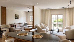 Uma sala de estar moderna com uma mesa de jantar de vidro, assentos confortáveis e vista através de uma grande janela.