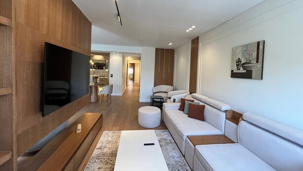 Uma sala de estar moderna com televisão de tela plana, sofá modular e mesa de centro.