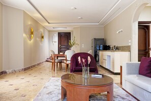 A modern living room with a glass coffee table, a sofa, and a dining area with chairs. - Luxury APT - 3BR - South Teseen I (New Cairo)