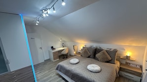 Une chambre à coucher moderne, comprenant un lit, des tables de chevet, un bureau et une armoire.