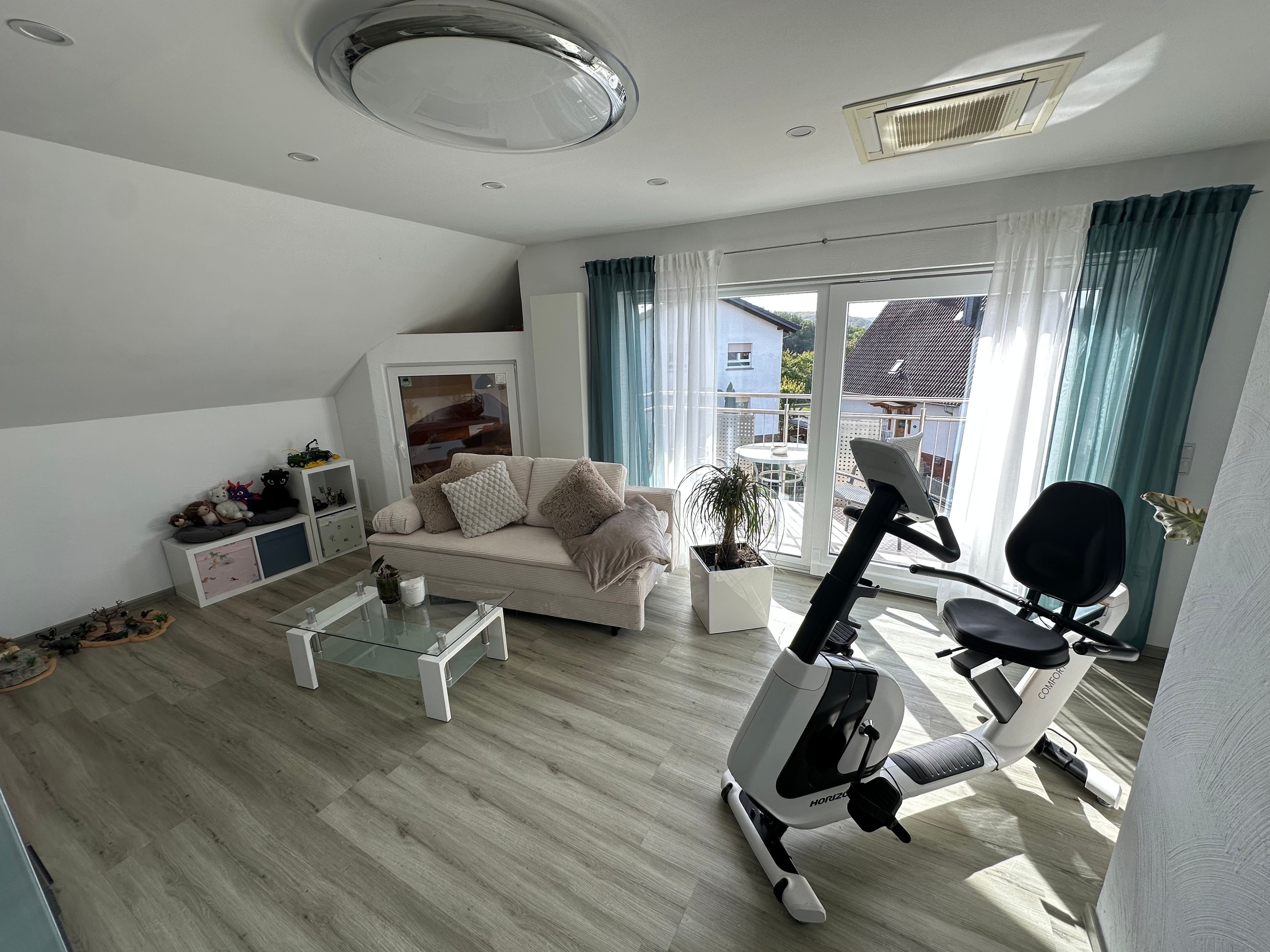 A modern living room with a sofa, coffee table, and exercise bike.