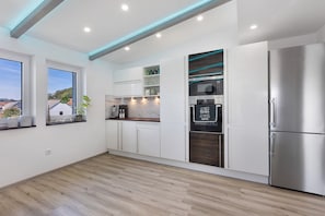 A modern kitchen with white cabinetry, a stainless steel refrigerator, and a built-in microwave.