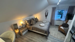 Une chambre à coucher avec un lit, une table de chevet, une chaise et une vue sur l’extérieur.